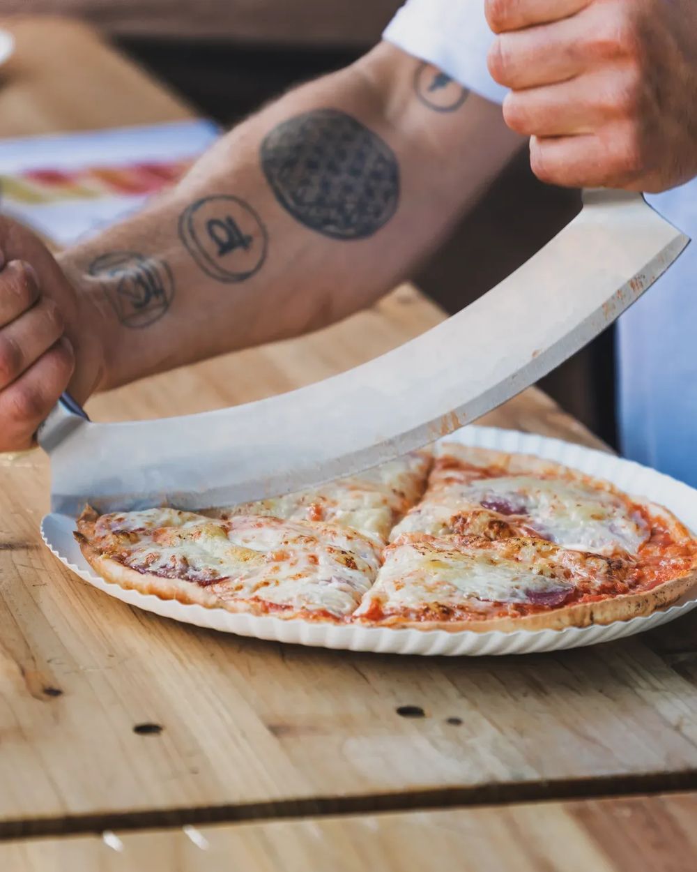 Eine frisch gebackene Pizza wird mit dem Wiegemesser geschnitten